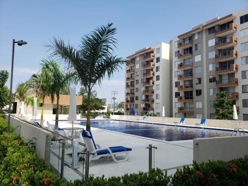 a pool with chairs and a palm tree and buildings at DoBBY HOUSE APARTAMENTO EN PEÑALISA in Girardot