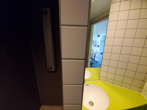 bagno con lavandino giallo e specchio di Auberge de Jeunesse HI Strasbourg 2 Rives a Strasburgo