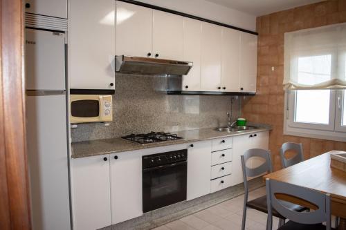 een keuken met witte kasten en een kookplaat oven bij Apartamento PLAYA ESTEIRO in Muros