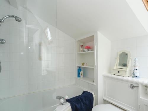 a white bathroom with a shower and a toilet at Glan Aber in Amlwch