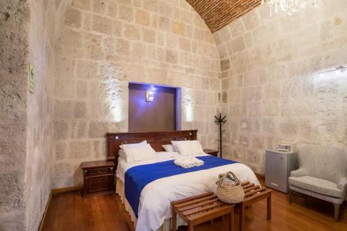 a bedroom with a large bed in a stone wall at Hotel Casona Solar in Arequipa