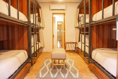 a room with four bunk beds with a chair in it at Selina Poc Na Isla Mujeres in Isla Mujeres
