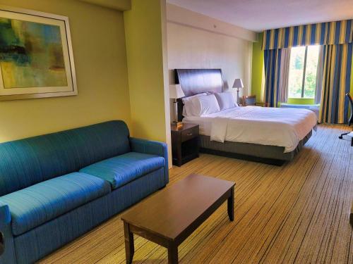 a hotel room with a bed and a couch at Holiday Inn Express & Suites Wilson-Downtown by IHG in Wilson