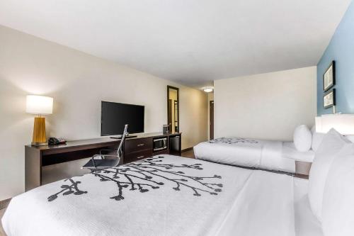a hotel room with two beds and a desk at Sleep Inn & Suites Ames near ISU Campus in Ames