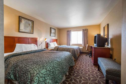 a hotel room with two beds and a television at Rodeway Inn & Suites Nampa in Nampa
