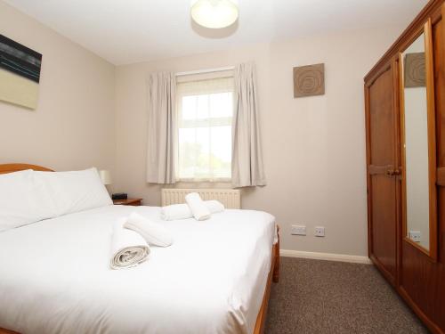 1 dormitorio con 1 cama con sábanas blancas y ventana en Anvil House, en Weymouth