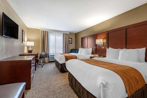 a hotel room with two beds and a television at Comfort Inn & Suites Muncie Near University in Muncie