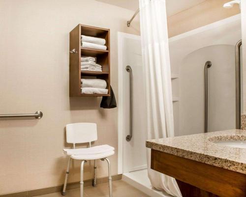La salle de bains est pourvue d'un lavabo et d'une chaise à côté d'une douche. dans l'établissement Comfort Inn & Suites Sturbridge-Brimfield, à Sturbridge