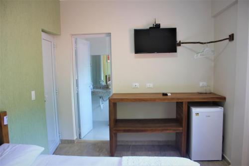 a room with a desk with a television on the wall at Residencial Águas de Bare in São Sebastião