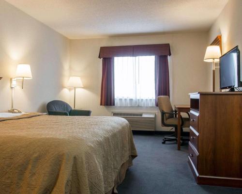 a hotel room with a bed and a desk and a television at Quality Inn Hudsonville South in Hudsonville