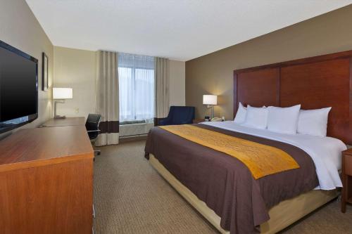 a hotel room with a bed and a flat screen tv at Comfort Inn & Suites in Taylor