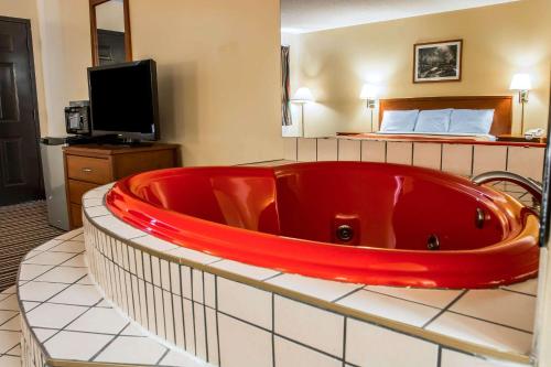 a large red tub in a hotel room with a bed at Econo Lodge in Paw Paw