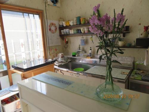 eine Küche mit einer Vase mit lila Blumen darin in der Unterkunft Guest House Miyazu Kaien - Vacation STAY 99191 in Miyazu