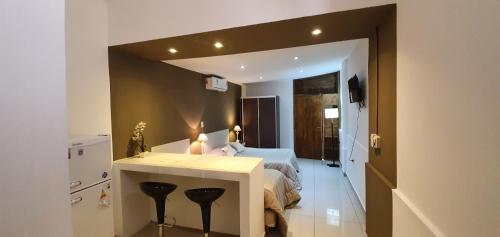 1 dormitorio con cama y barra con taburetes en Del Pilar II en La Rioja
