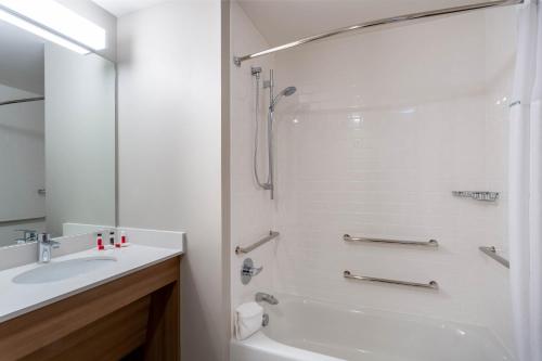 a white bathroom with a shower and a sink at Microtel Inn & Suites by Wyndham Amsterdam NY in Amsterdam