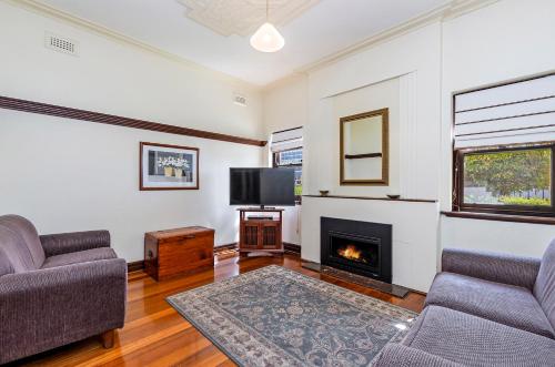 a living room with two couches and a fireplace at Fairholme Apartment in Warrnambool