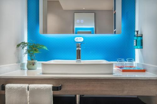 a bathroom with a white sink and a blue wall at Holiday Inn Express Changsha South Railway Station, an IHG Hotel in Changsha