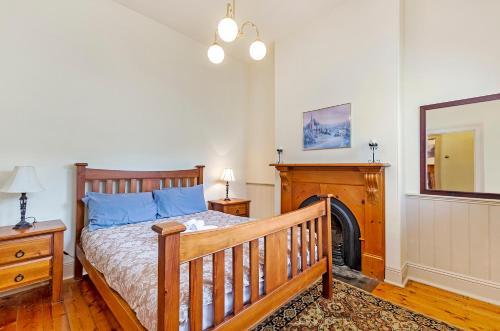 a bedroom with a wooden bed and a fireplace at Fairholme Townhouse in Warrnambool