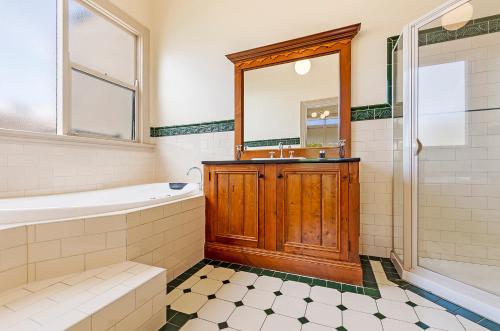 a bathroom with a tub and a sink and a mirror at Fairholme Townhouse in Warrnambool