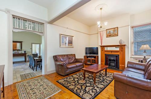 a living room with leather furniture and a fireplace at Fairholme Townhouse in Warrnambool