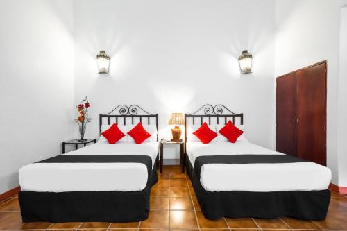 2 camas en una habitación con almohadas rojas en Capital O El Nito, en Oaxaca City