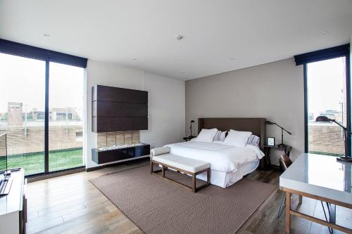 1 dormitorio con cama blanca y ventanas grandes en Attik Luxury Apts, en Bogotá