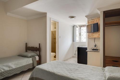 a bedroom with two beds and a television in it at Hotel Estrela Do Vale in Ipatinga