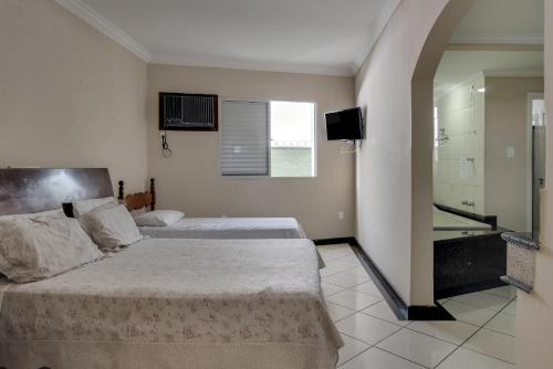 a bedroom with two beds and a television in it at Hotel Estrela Do Vale in Ipatinga
