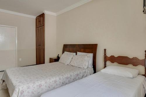 two beds in a bedroom with white walls at Hotel Estrela Do Vale in Ipatinga