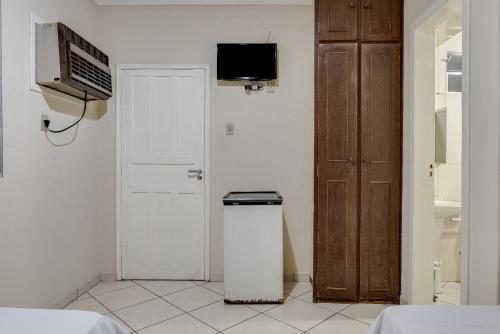 a room with a trash can and a door with a television at Hotel Estrela Do Vale in Ipatinga