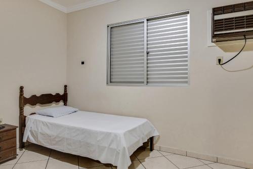 a white bedroom with a bed and a window at Hotel Estrela Do Vale in Ipatinga