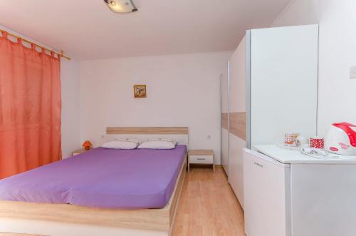 a bedroom with a purple bed in a white room at Rooms Mira II in Vodice