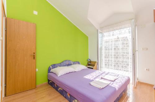 ein Schlafzimmer mit einem lila Bett und einer grünen Wand in der Unterkunft Apartments Mira I in Vodice