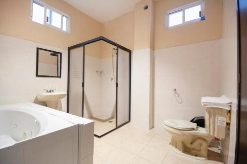 a bathroom with a shower and a toilet and a sink at Hotel Spa Shalam in Coatepec
