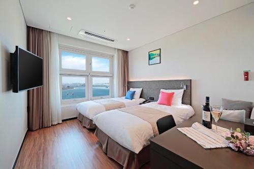 a hotel room with two beds and a flat screen tv at Airsky Hotel Incheon in Incheon
