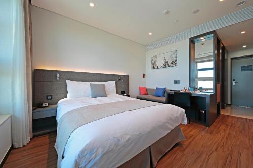 a hotel room with a large bed and a desk at Airsky Hotel Incheon in Incheon