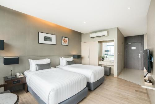 a hotel room with two beds and a television at Altera Hotel and Residence by At Mind in Pattaya Central