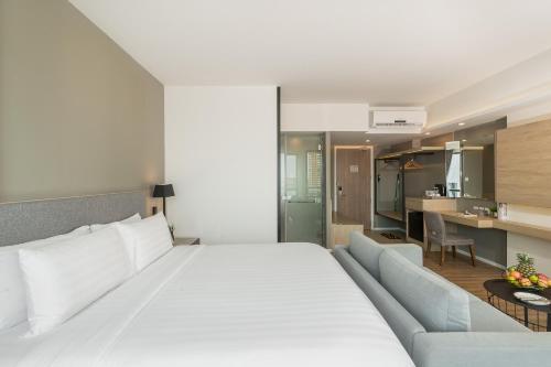a bedroom with a large white bed and a couch at Hotel Amber Pattaya in Pattaya Central