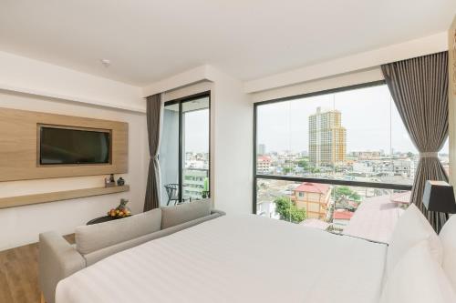a bedroom with a white bed and a large window at Hotel Amber Pattaya in Pattaya Central
