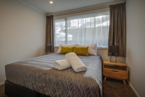 a bedroom with a bed with two pillows and a window at Dusky Motels in Te Anau