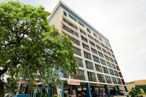 a large building with a tree in front of it at OYO 458 Nakorn Siam Boutique in Pattaya