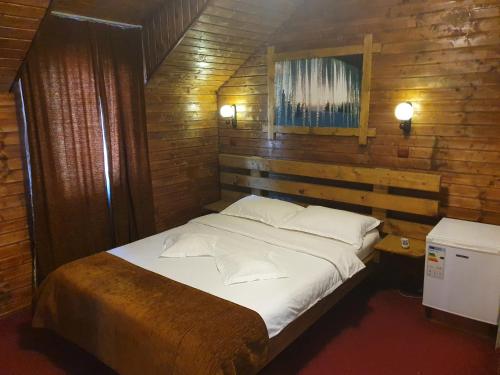 a bedroom with a bed in a wooden wall at Pensiunea Melinda in Petroşani