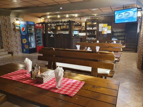 a restaurant with wooden benches and a table with a red and white table at Pensiunea Melinda in Petroşani