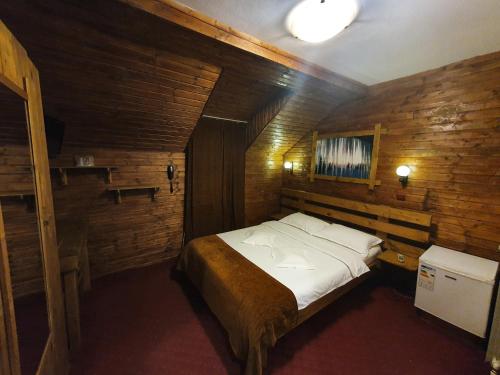ein Schlafzimmer mit einem großen Bett in einem Holzzimmer in der Unterkunft Pensiunea Melinda in Petroşani