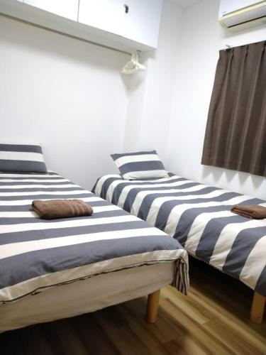 two beds in a room with black and white stripes at Rimon Apartment in Tokyo