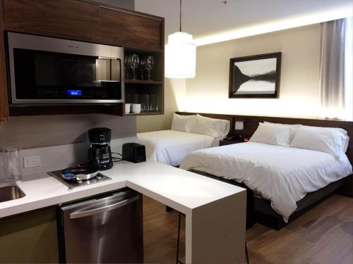 una camera d'albergo con due letti e una cucina di Staybridge Suites - Guadalajara Novena, an IHG Hotel a Guadalajara