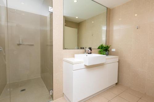 a bathroom with a sink and a shower and a mirror at 4 Bedroom Luxury City Penthouse Apartment in Wagga Wagga