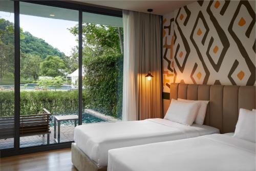 two beds in a hotel room with a balcony at The Peri Hotel Khao Yai in Phayayen