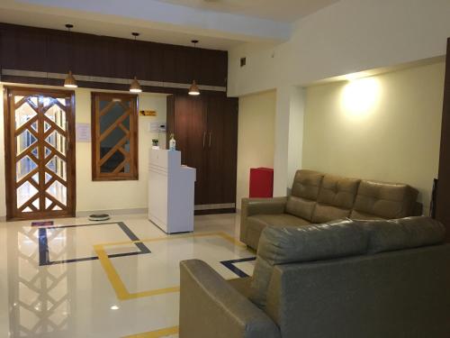 a living room with two couches and a refrigerator at Grand Suites Srirangam in Tiruchchirāppalli