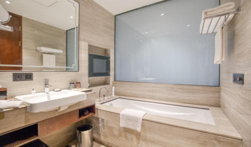 a bathroom with a large tub and a sink at Fulitai International Hotel in Yantai